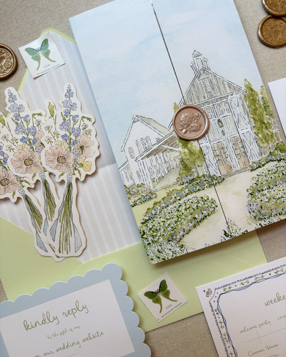 Wedding stationery set with watercolor floral design, venue illustration, and decorative elements on a textured surface